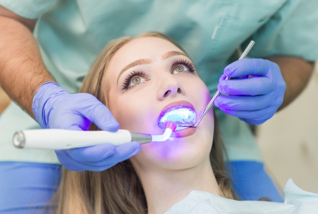 dentist-doing-procedure-with-dental-curing-uv-light-clinic_109285-3740